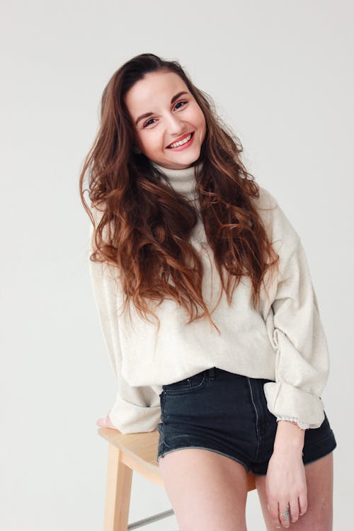 Free Beautiful Model With Brown Wavy Hair Sitting on a Wooden Chair Stock Photo