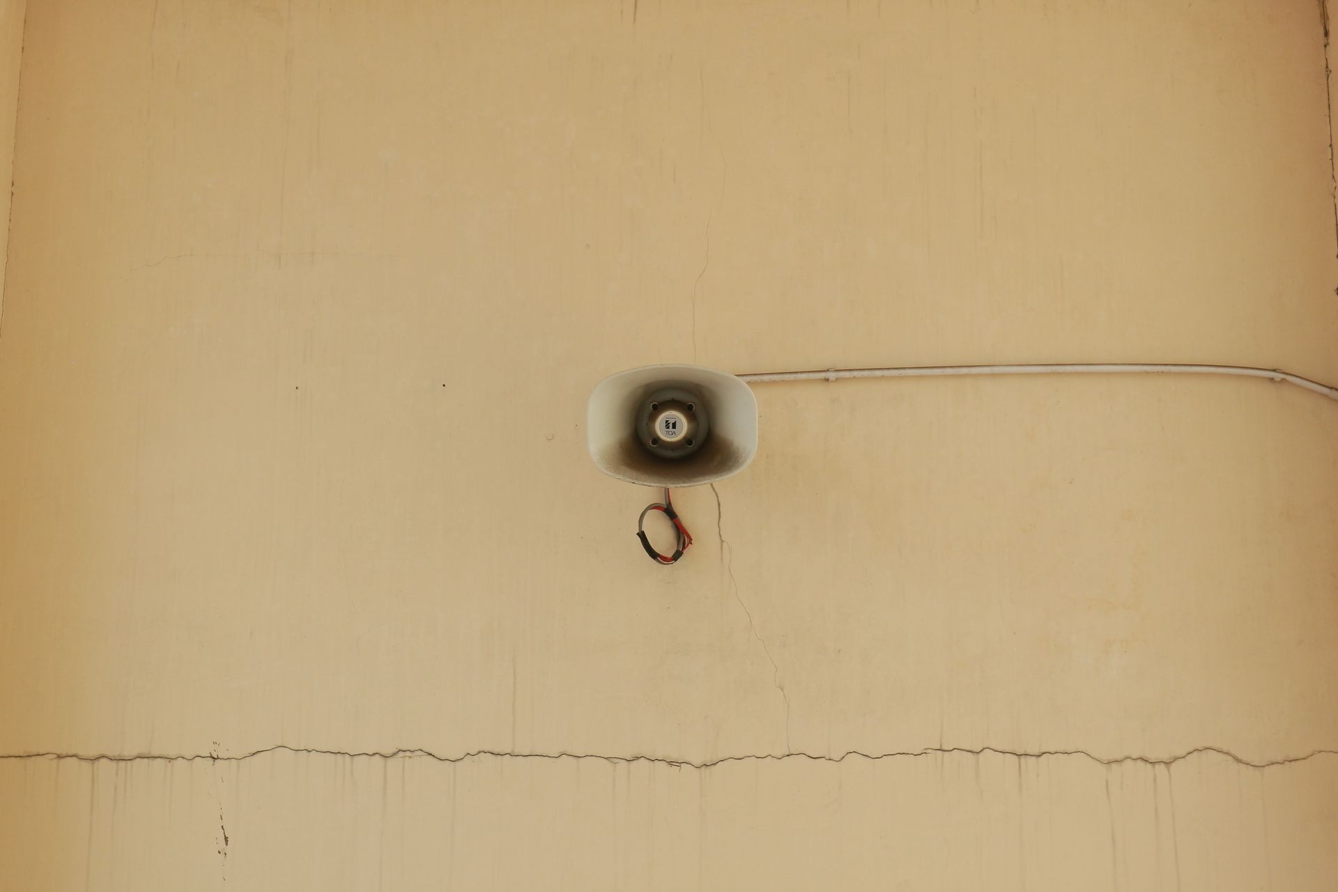A mounted megaphone on a cracked wall highlights urban decay and communication themes.
