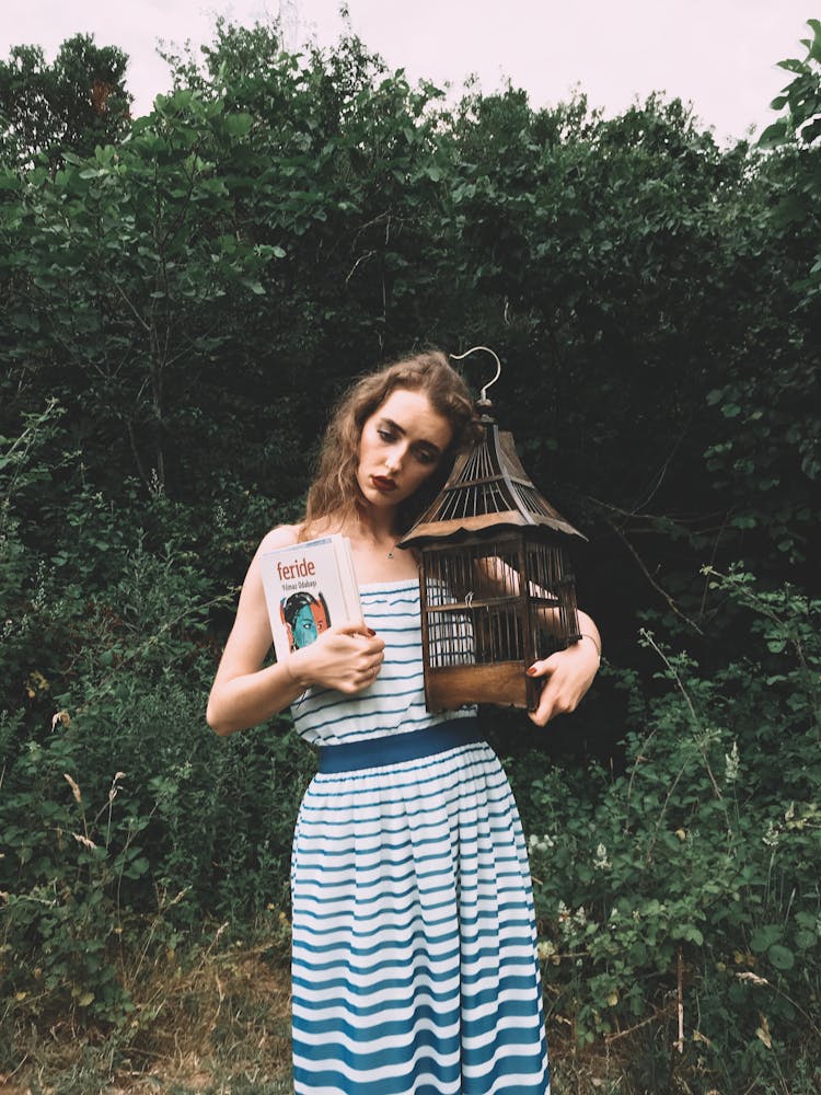 Sad Woman Holding A Book And A Birdcage