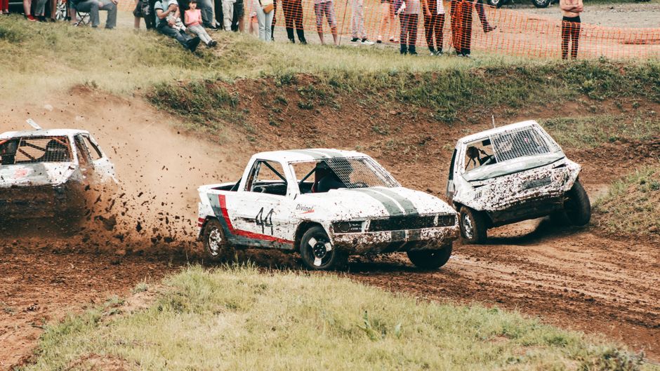 Exciting off-road racing action captured on a muddy dirt track, showcasing competitive sports vehicles.