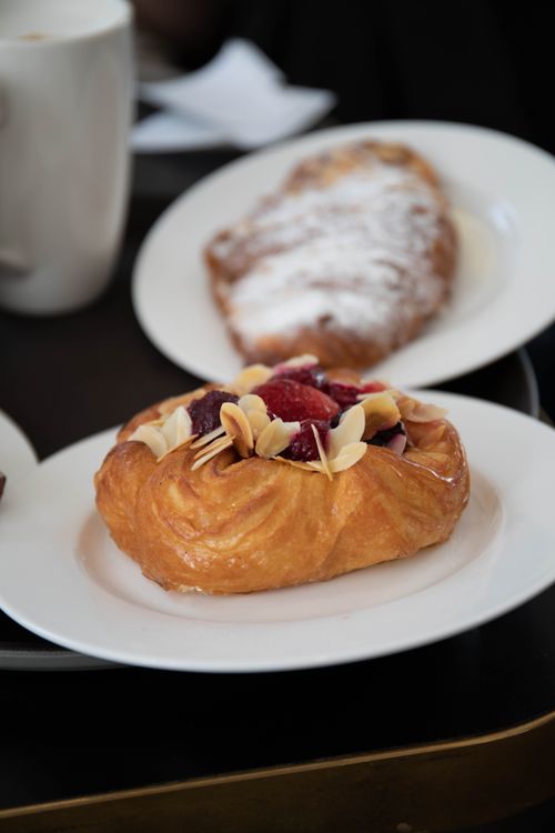 Free Close-up of a Danish pastry topped with almonds and berries on a ceramic plate. Stock Photo