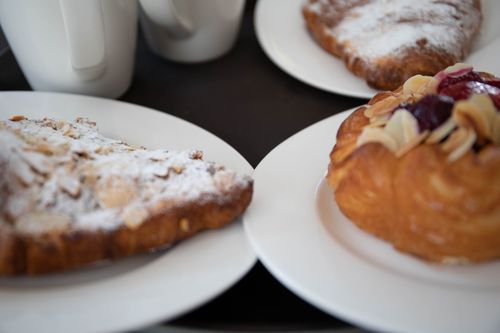 Free Enticing close-up shot of assorted pastries on plates with a warm ambiance. Stock Photo