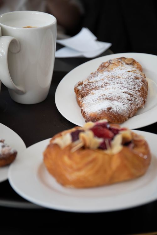 Free Tempting pastries and a hot coffee cup on a cozy cafe table. Stock Photo