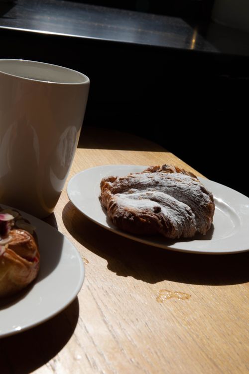 Free Delicious croissant and a mug of coffee on a sunlit wooden table, perfect breakfast scene. Stock Photo