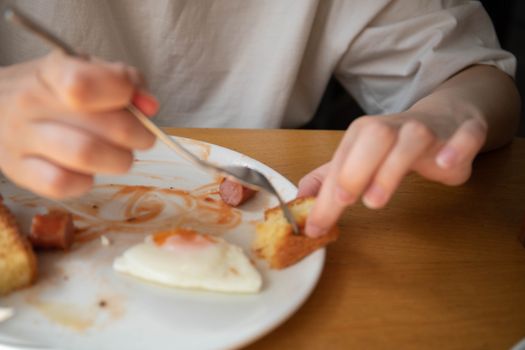 A person holding bread on a plate with an egg and sauce. Relaxed breakfast vibe.