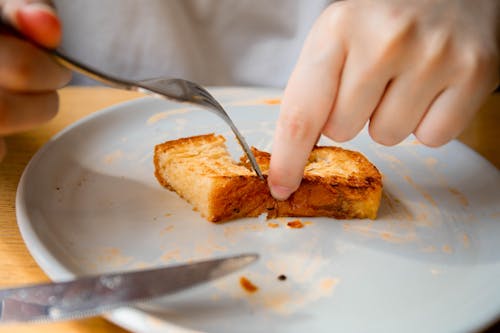 Free A Person Holding Brown Toasted Bread on White Ceramic Plate Stock Photo