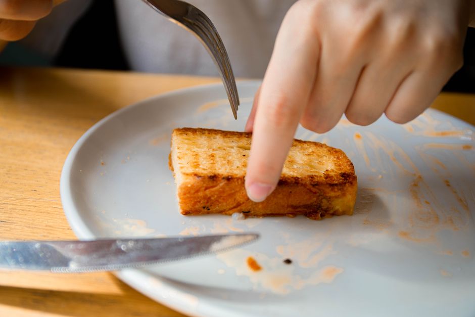 Thick slices of golden-brown Texas toast stacked on a plate, edges crisp and centers soft, flecked with melted garlic butter and parsley.