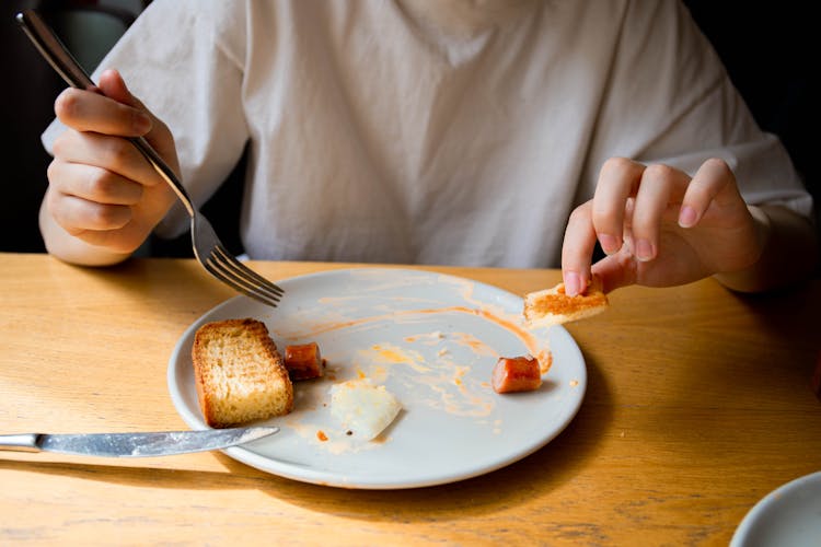 Person Holding Stainless Fork And Bread 