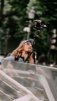 A photographer with long hair adjusts his camera on a tripod during a street shoot in Kyiv.
