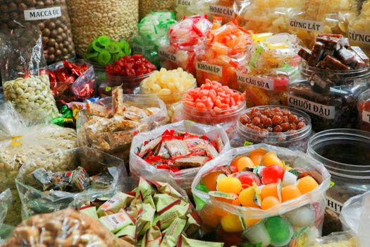 Colorful variety of traditional market sweets in plastic containers and bags.