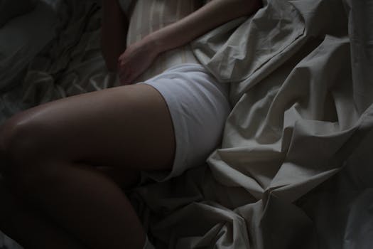 A person lying on crumpled fabric, captured in a moody, relaxed atmosphere.