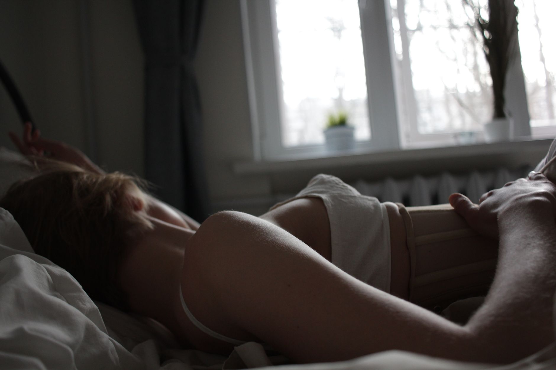 A serene scene of a woman resting in bed bathed in soft morning light.