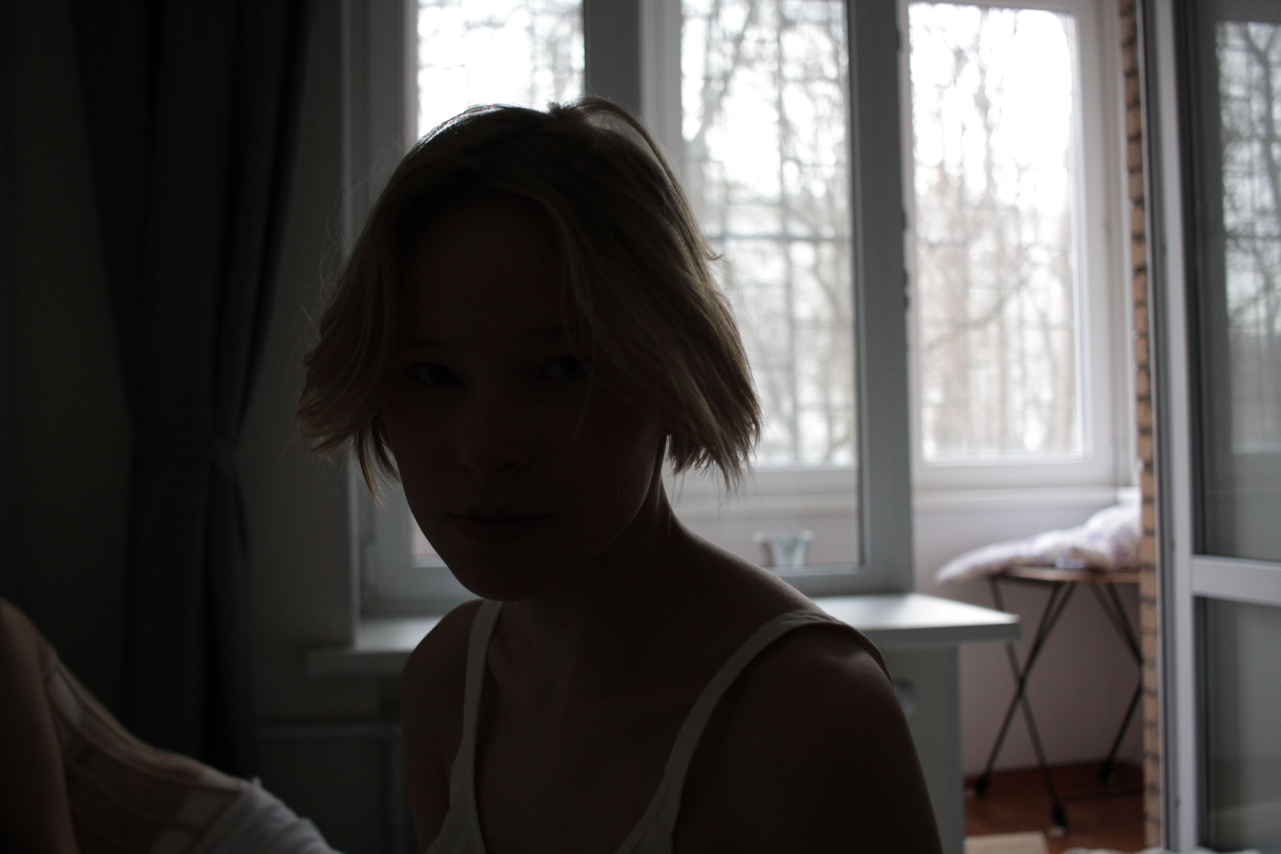 Moody silhouette of a young woman indoors with soft lighting.