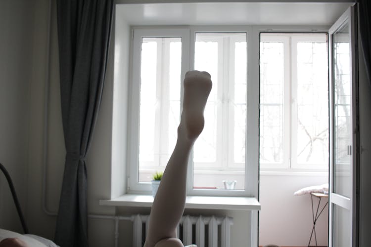 Female Leg In White Tights Held Up In The Bedroom 