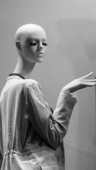 Stylish mannequin with eyelashes in a gray jacket, elegantly posed in a store display.