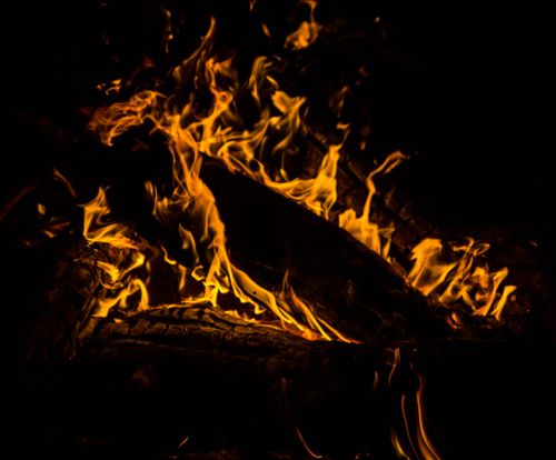 Free A captivating close-up of blazing flames dancing around firewood in the dark. Stock Photo
