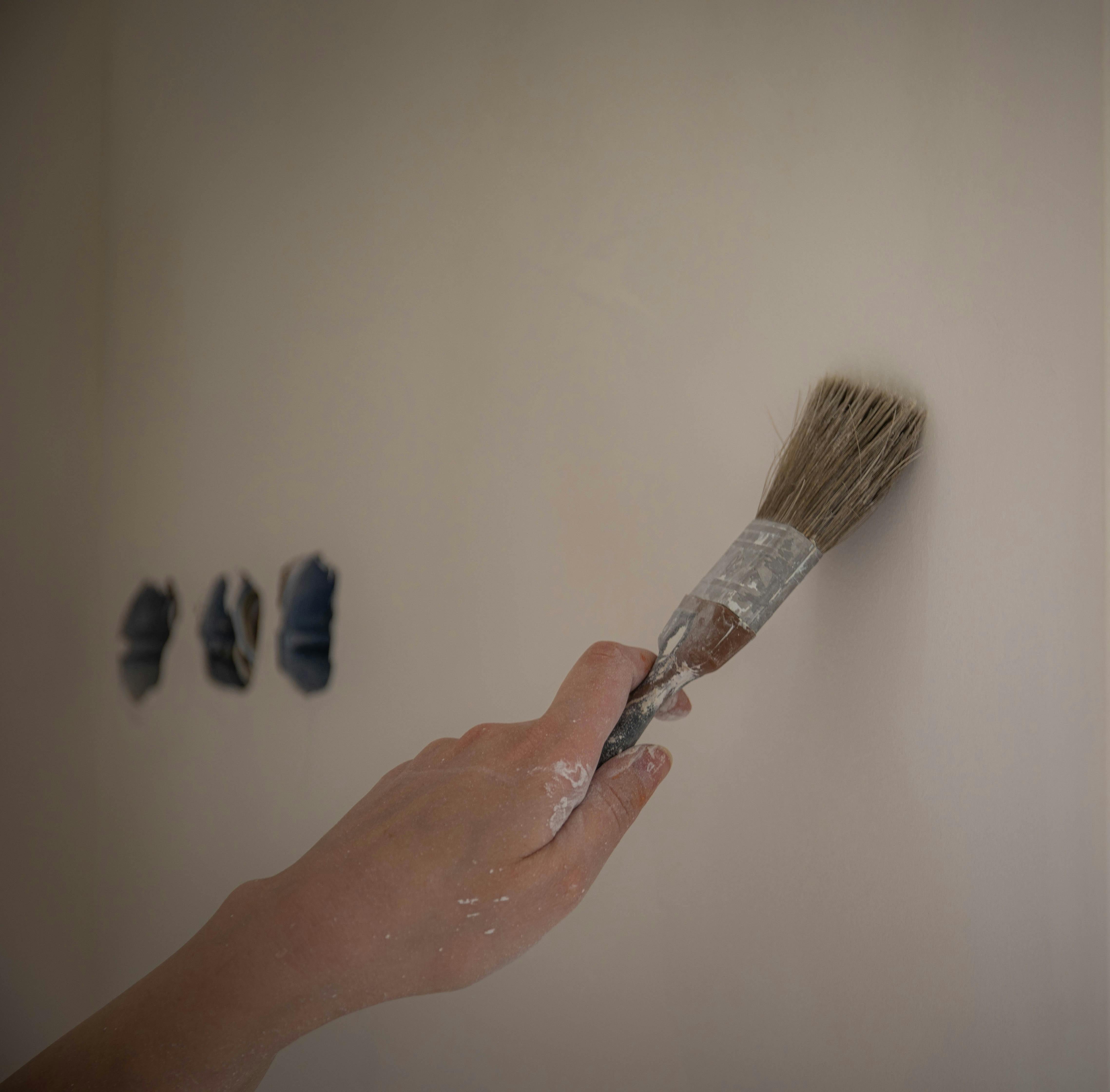 Farbmuster und Testkarten an einer Wand im Tageslicht, daneben Textilien zur Unterton-Prüfung