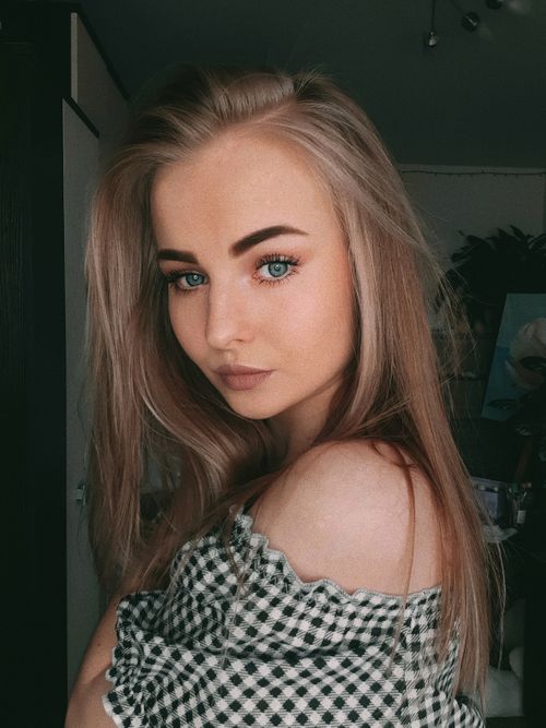 Free Close-up portrait of a young woman with blonde hair posing indoors in a checkered top. Stock Photo