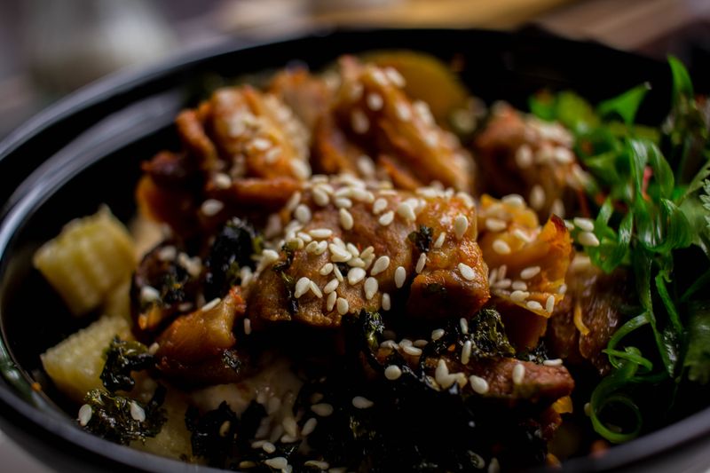 Dak galbi spicy stir-fried chicken glazed in red gochujang sauce, topped with sesame seeds and herbs