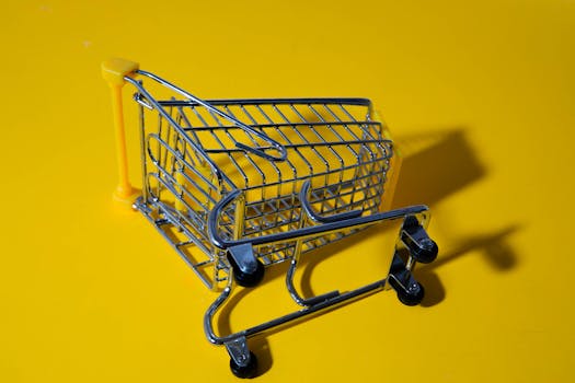 Close-up of a toy shopping cart on a vivid yellow surface, casting shadows.