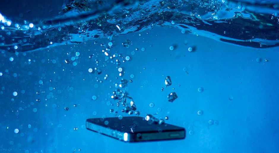 Smartphone submerged in a glass of water showing liquid damage - insurance policy for mobile phones Smartphone submerged in a glass of water showing liquid damage - insurance policy for mobile phones
