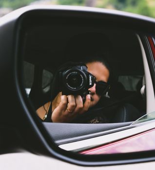 Photographer captures their reflection in car mirror using DSLR camera.