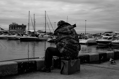 Man Sitting on a Pier and Fishing 