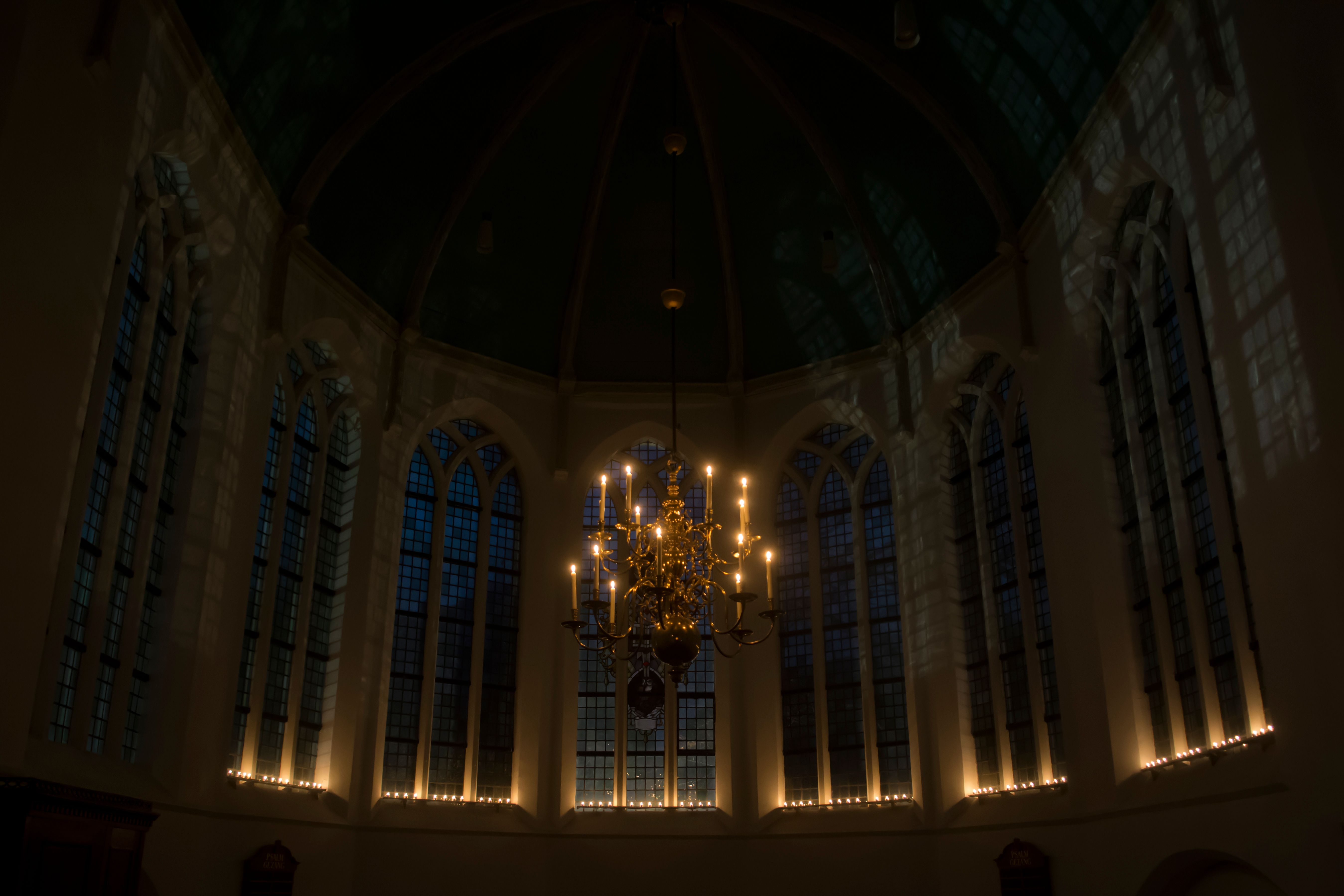 Dimly lit Gothic church interior with a chandelier, glowing with candlelight creating a serene ambiance.