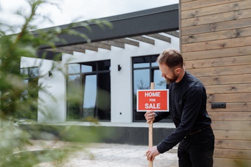 Free A Man in Black Long Sleeves Putting the Signage Outside a House Stock Photo