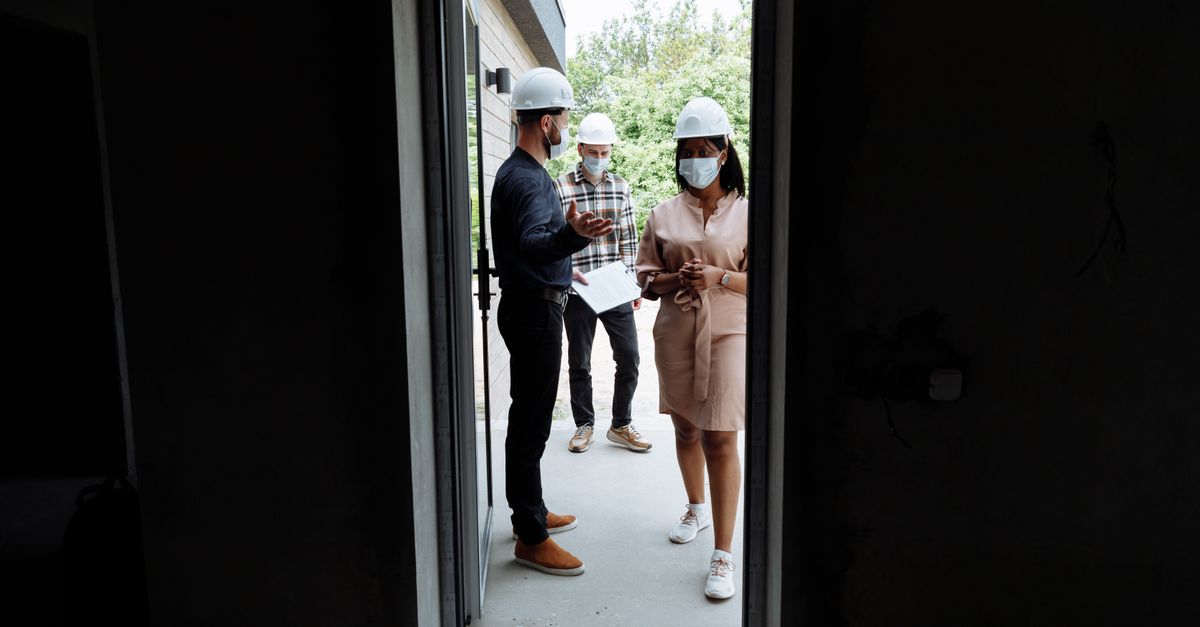 Builder meeting clients at a construction site to discuss a project — trade directories support credibility during the homeowner shortlisting process