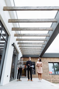 Clients touring a modern home with a real estate agent, all wearing masks for safety.