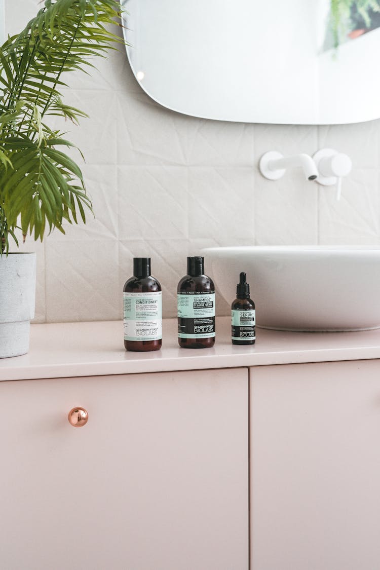 Shampoo And Conditioner Bottles On A Pastel Pink Cabinet 