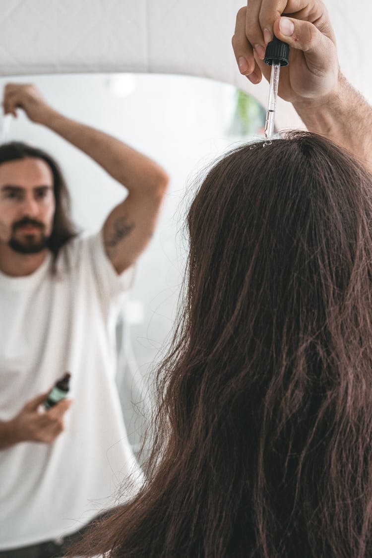 Man Applying Serum On Top Of His Long Hair