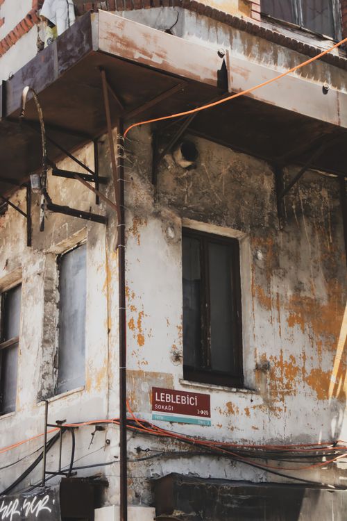 Free Aged and worn corner of an urban building showcasing peeling paint and cables in daylight. Stock Photo