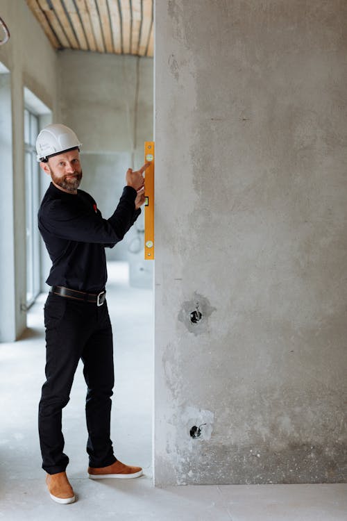 Free Man Holding a Spirit Level against a Concrete Wall Stock Photo