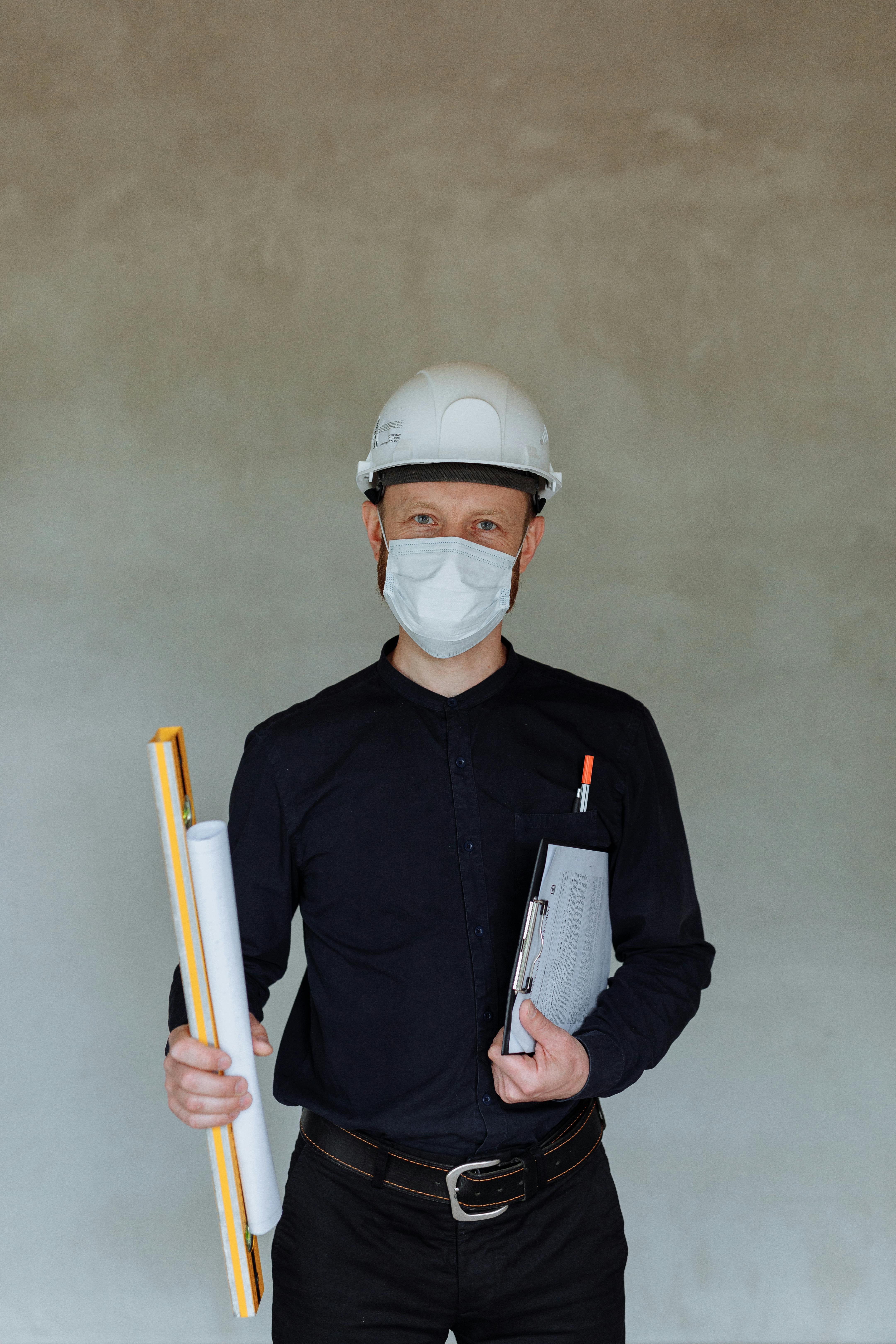portrait of an architect wearing a hard hat and a face mask