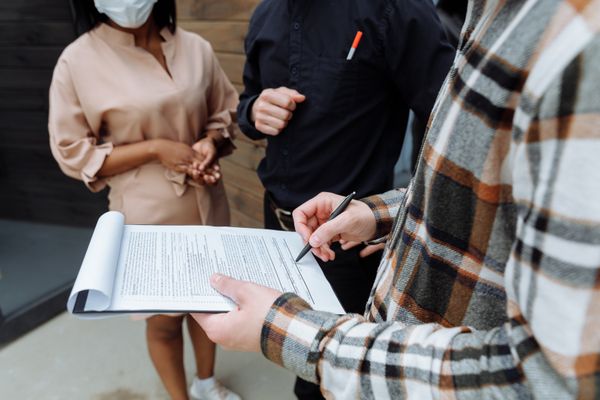 Three adults in an office setting discussing and signing a document