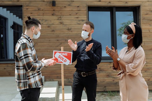 Group of people celebrating real estate sale outdoors with sold sign.