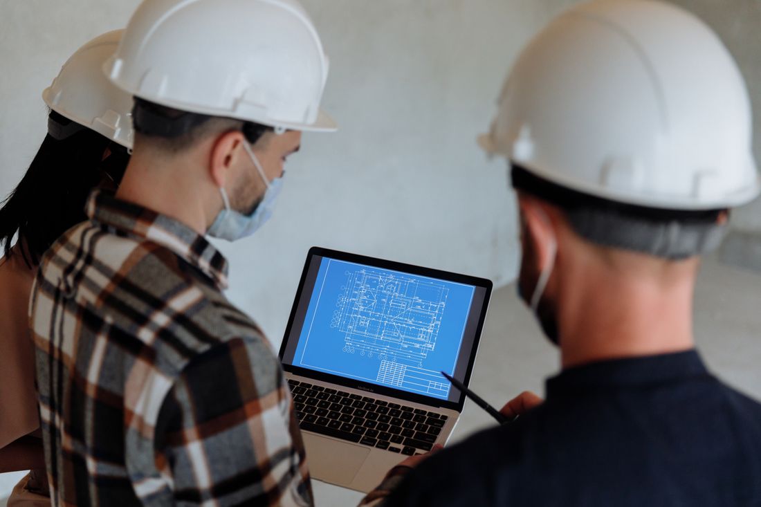 Engineers in hard hats reviewing a construction blueprint