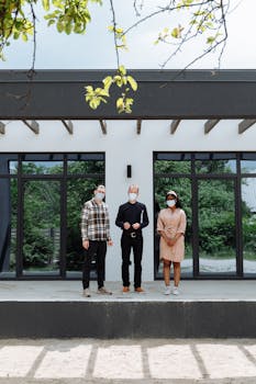 Three people with masks standing outside a modern building.