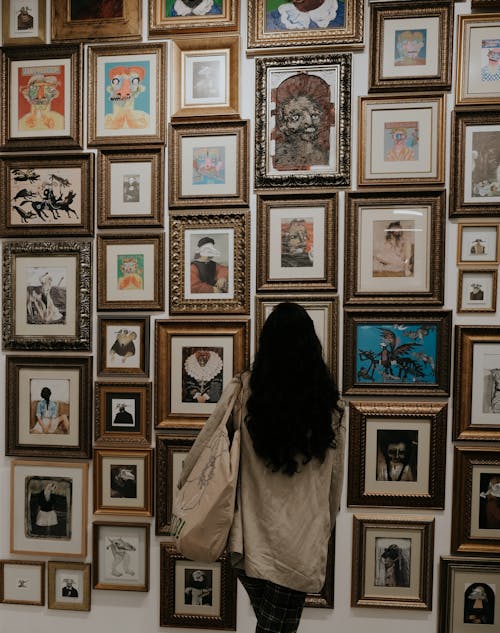 Back View of a Person Looking at Art in Picture Frames