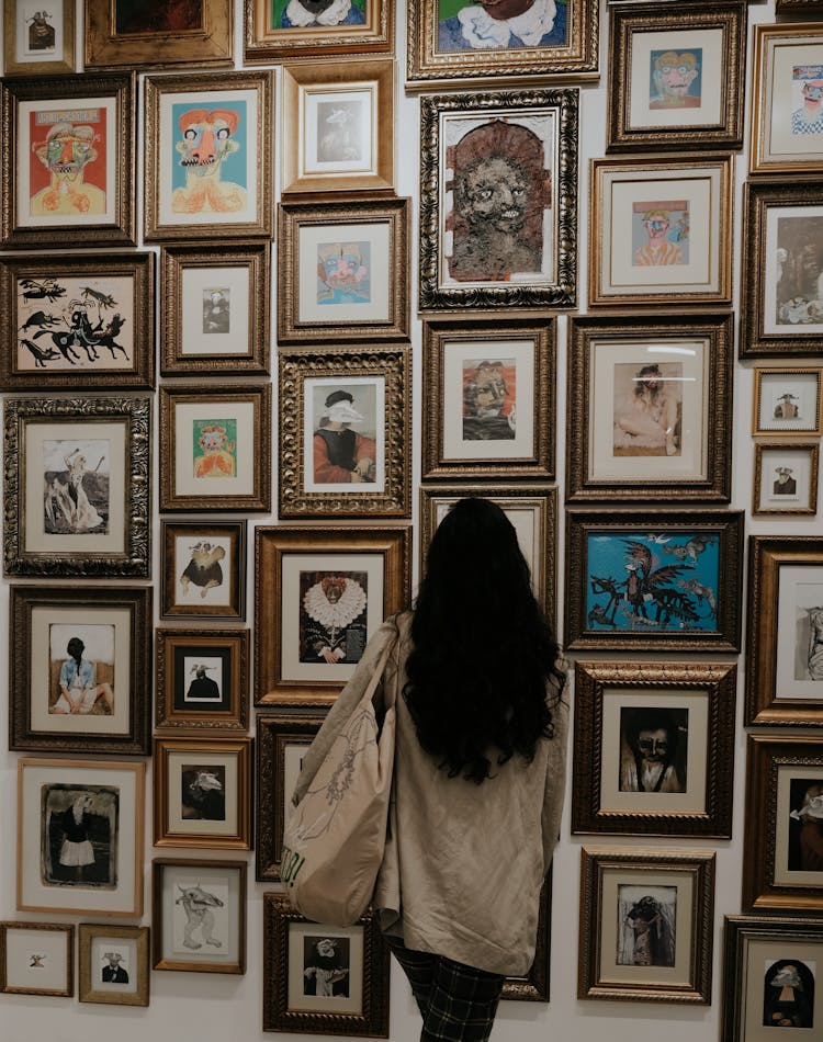 Back View Of A Person Looking At Art In Picture Frames