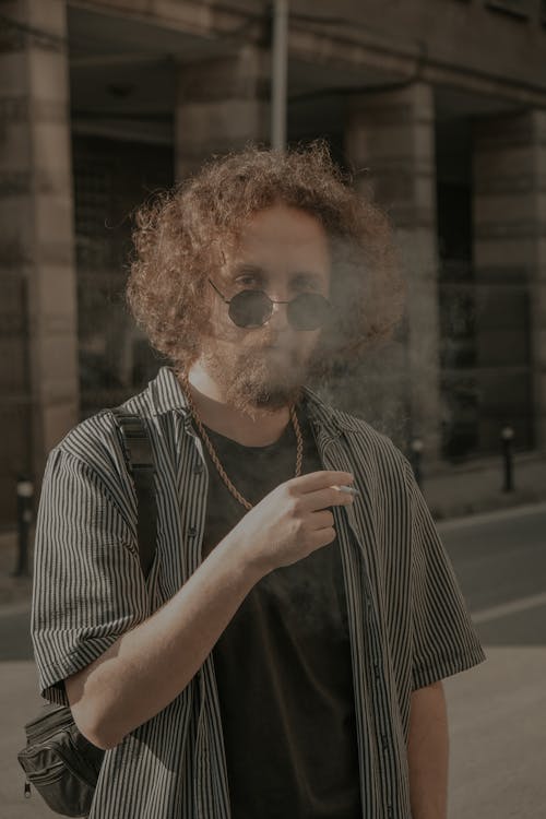 Man in Black Sunglasses Exhaling Smoke From a Cigarette