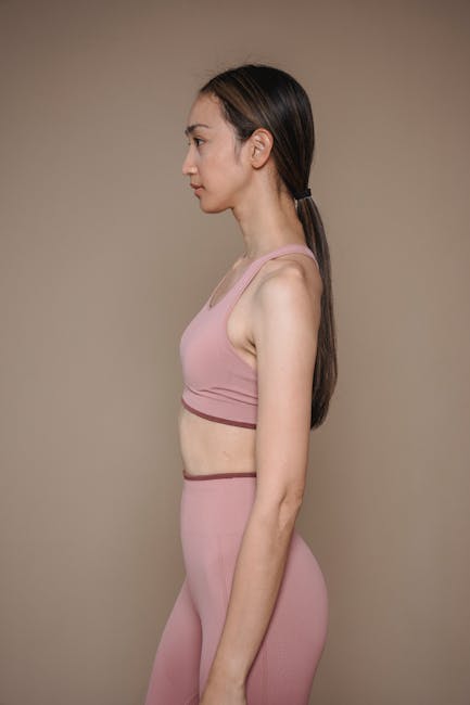 Side profile of a woman in pink sportswear standing against a neutral background.