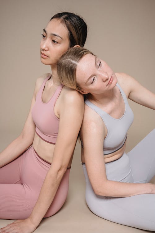 Women Sitting Back to Back Leaning on Each Other 