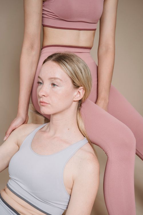 Free Two women in pastel activewear posing in a studio with a beige background. Stock Photo