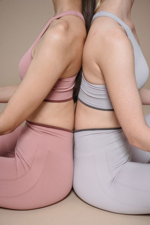 Free Two women in sportswear sitting back to back in a yoga pose. Stock Photo