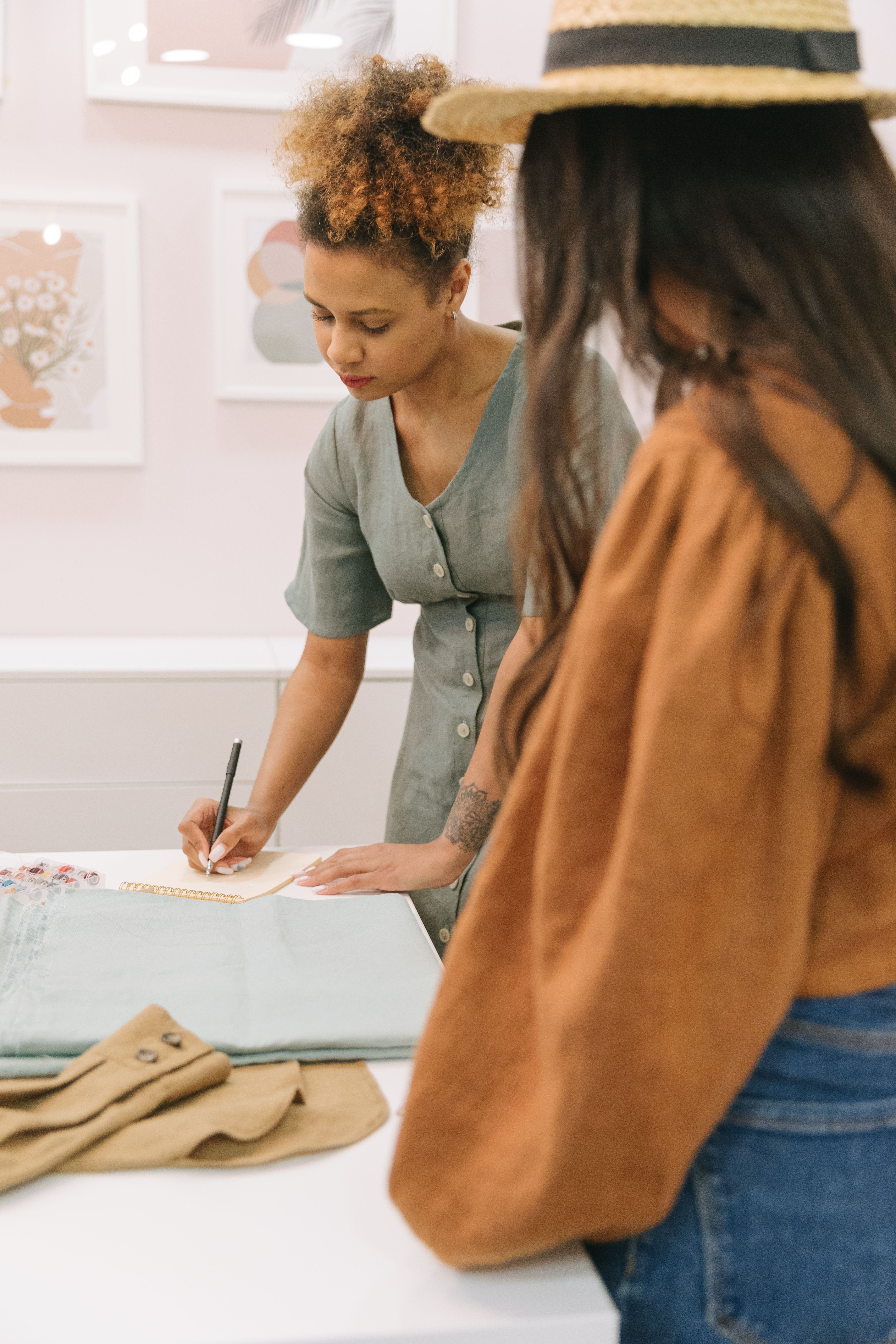 Two female fashion designers working on new clothing designs in a stylish studio environment.