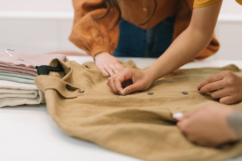 People Working on a Brown Button Down Shirt on a Table