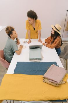 A diverse team of women fashion designers brainstorming ideas in a modern atelier.